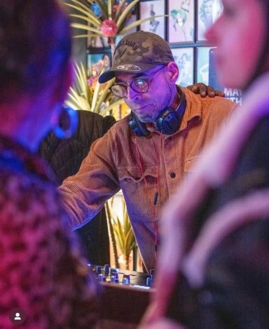 DJ performing live at an In2Groove Radio event with colorful stage lights.