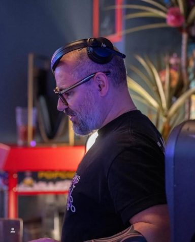 DJ performing live at an In2Groove Radio event with colorful stage lights.